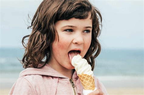Girl With Dark Hair Looking Away And Licking Ice Cream While Spending