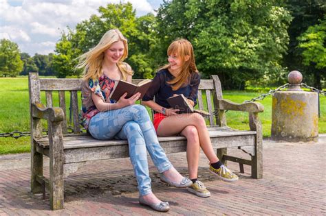 Girls Sitting On Wooden Bench In Park Reading Books Stock Image Image
