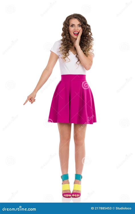 une jeune femme excitée aux talons hauts colorés pointe vers le bas