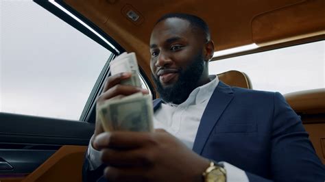 Portrait Of Happy African American Man Smelling Dollars At Luxury Car