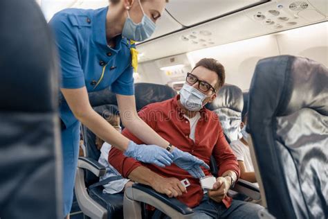 Man In Protective Face Mask Looking At Female Flight Attendant Helping