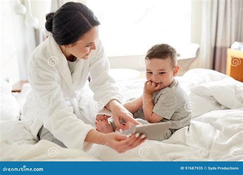 mère et fils avec le smartphone dans le lit à l hôtel image stock