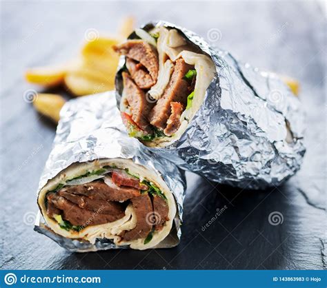 greek gyro wrapped in foil cut in half and served with