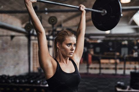 young woman lifting weights   head   gym