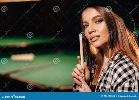 a girl in a hat in a billiard club with a cue in her hands billiards