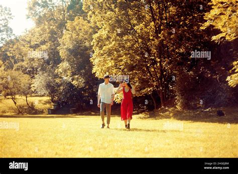 couple running in the forest field girl in a long red dress and hat