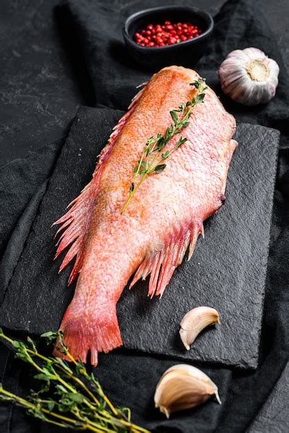 Raw Red Sea Bass On A Stone Board With Thyme Black Background Top