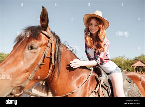 glücklich ziemlich junge rothaarige cowgirl reiten auf der ranch