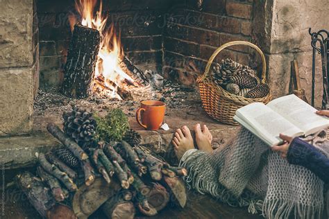 cozy home woman reading a book in front fireplace stocksy united