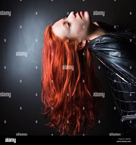 Pretty Redhead Young Woman Wearing Leather Jacket Leaning Back In Chair