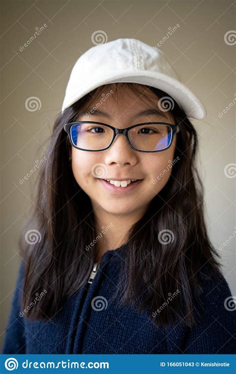 portrait of asian teen girl with eyeglasses and white cap stock image