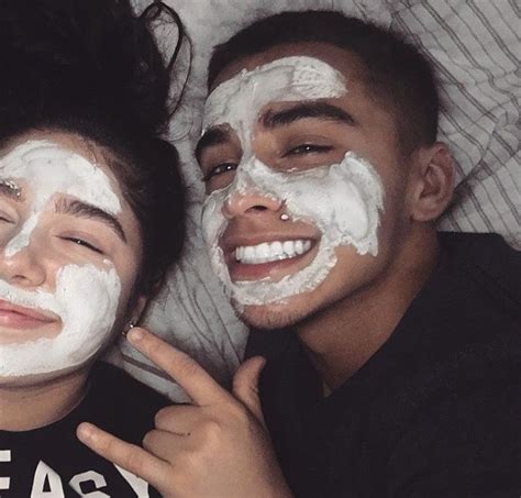 two people laying on a bed with white facial masks on their faces and
