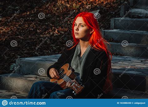redhead girl with long hair plays the ukulele perfect