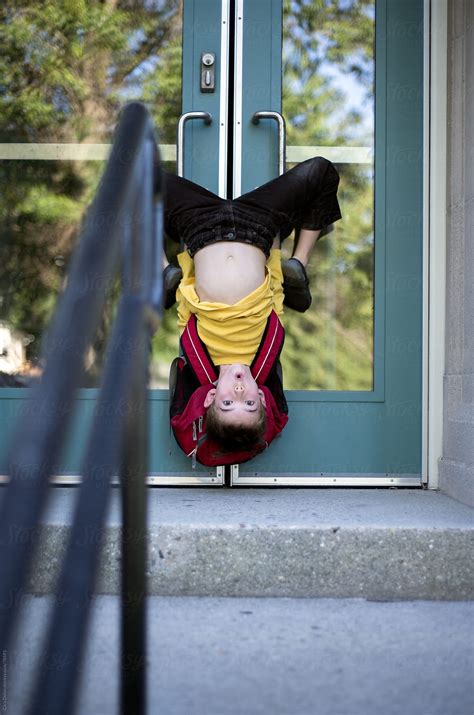 silly child hangs upside    doors   school  stocksy