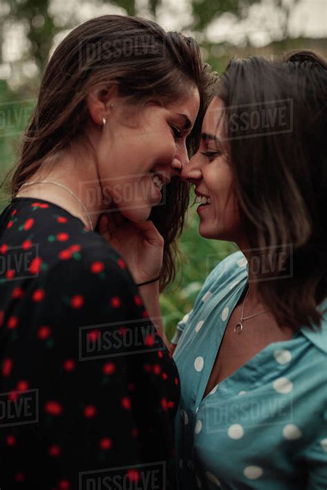 Two Young Lesbian Women Embraced Kissing On The Field Wearing Dresses