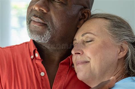 Close Up Of Multiracial Senior Couple With Eyes Closed Embracing At