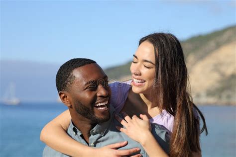 Happy Interracial Couple Laughing On The Beach On Vacation Stock Image