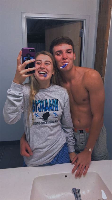 A Man And Woman Brushing Their Teeth In Front Of A Bathroom Mirror