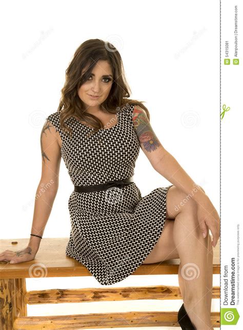 woman with tattoos in black and white dress legs crossed