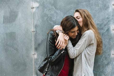 girl friends kissing  hugging    stocksy