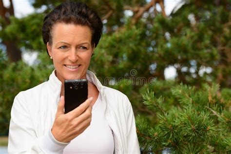 mature beautiful woman against healthy bushes in nature stock image