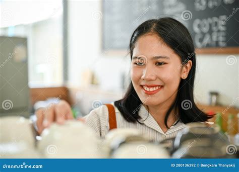 Friendly Asian Female Coffee Shop Staff Cleaning And Adjusting Coffee
