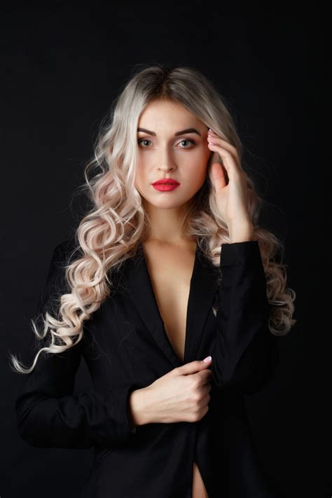 sexy blonde with long curly hair poses in black jacket in