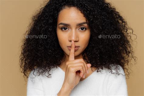 Confident Woman Makes Shush Gesture Keeps Fore Finger Over Lips Tells