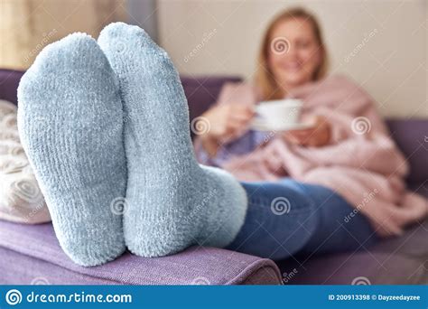 woman at home wearing cosy warm socks and wrapped in blanket lying on