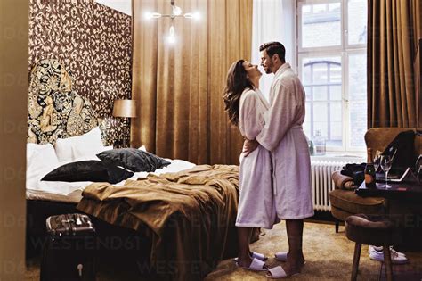 Side View Of Romantic Couple Embracing While Standing By Bed In Hotel