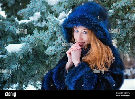 Russian Female Beauty In Blue Fur Coat On Blue Spruce Background