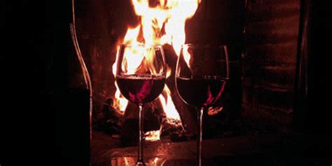 Гиф анимация Два бокала с вином стоят на фоне камина с огнем