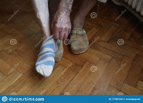 Senior Man Is Wearing Socks Into His Feet In The Bedroom