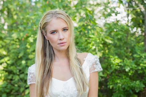 Pretty Smiling Blonde Bride Standing On A Bridge Looking Down Stock