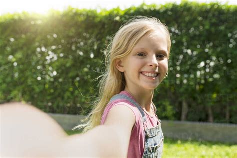 Cute Blonde Girl Taking Selfie In Garden Stockphoto