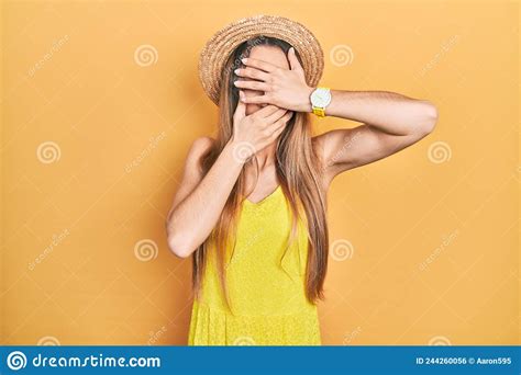Young Blonde Girl Wearing Summer Hat Covering Eyes And Mouth With Hands