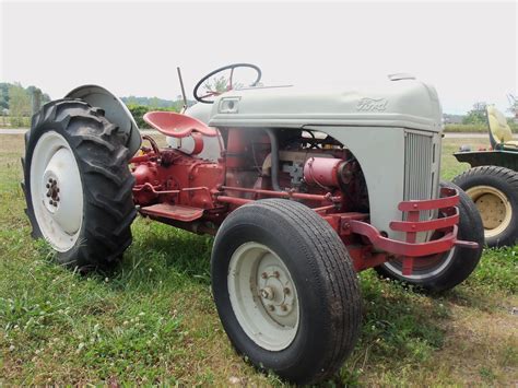 An Old Farmall Tractor Parked In The Grass With Two Large Tires On Its