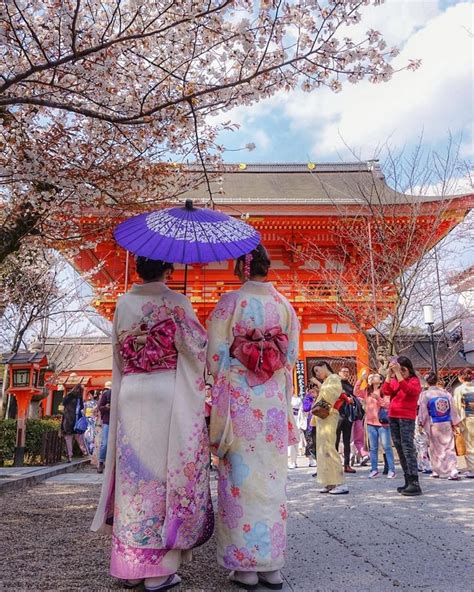 Two Women In Kimonos Are Holding An Umbrella