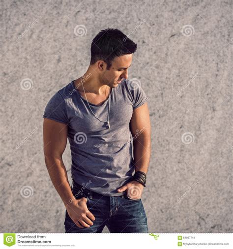 fashion model man wearing grey t shirt and jeans posing in