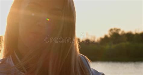 blonde girl shakes her long white hair at sunset by the river stock