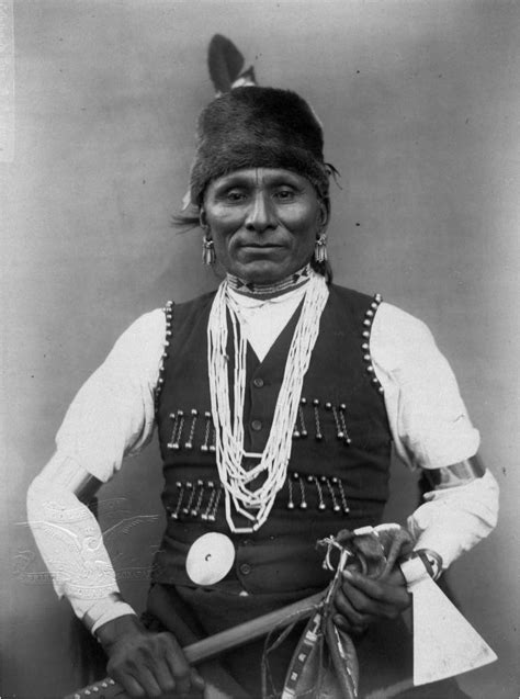 An Old Black And White Photo Of A Man In Native American Clothing