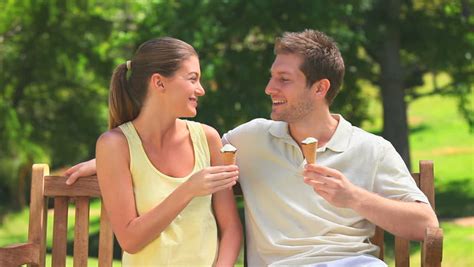 Pretty Couple Eating Ice Creams On A Park Bench Stock