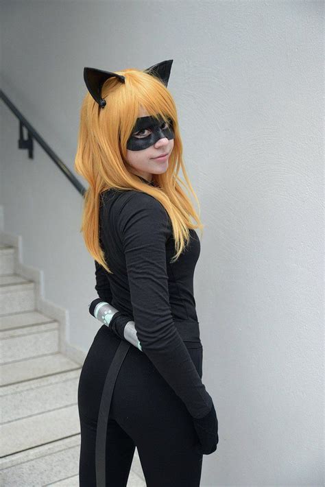a woman dressed in black cat costume standing next to stairs with her