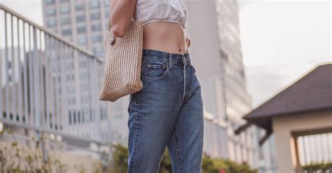Woman In White Tank Top And Blue Denim Jeans Standing On Gray Concrete