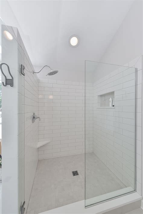 glass door walk in shower with white subway tile walls white and gray