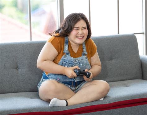 portrait of chubby asian woman sitting and holding a joystick looking