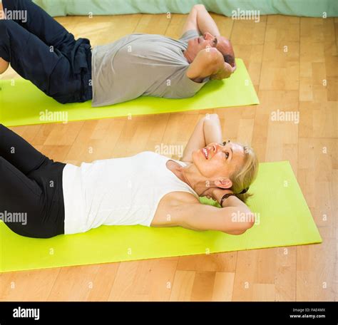 Positive Smiling Mature Couple Practicing Body Bending At Gym Stock