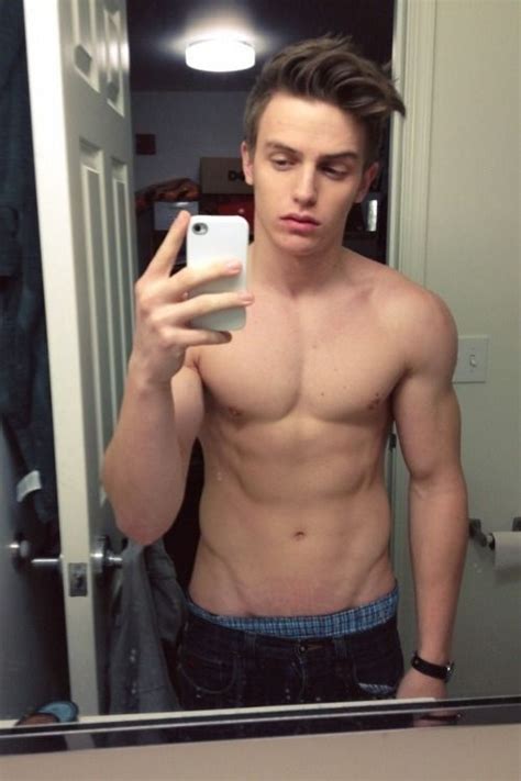 some cute shirtless guy in the bathroom taking a selfie of his body with his iphone