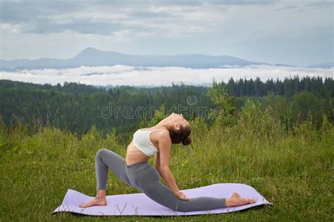 athletic woman doing flexible exercises on yoga mat outdoors stock