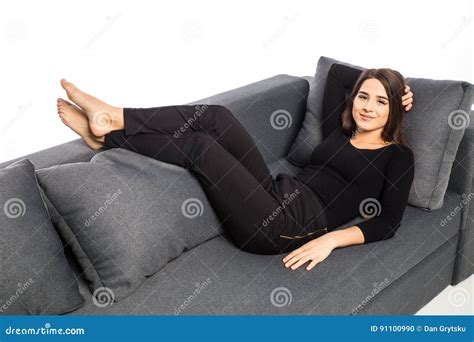 Calm Woman Lying On The Sofa In The Living Room With Her Feet Up Stock